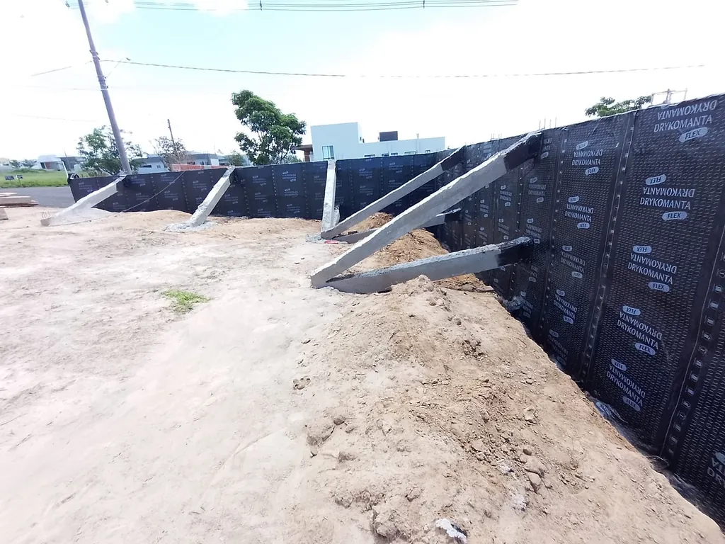 Muro de arrimo com manta preta aplicada e escoras de concreto